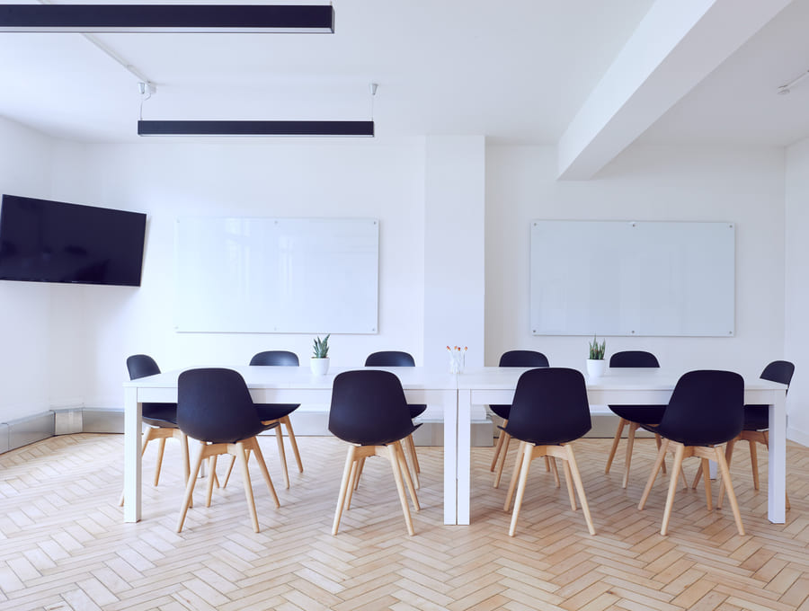 A quiet, uncluttered boardroom with a plain table, chairs and daylight