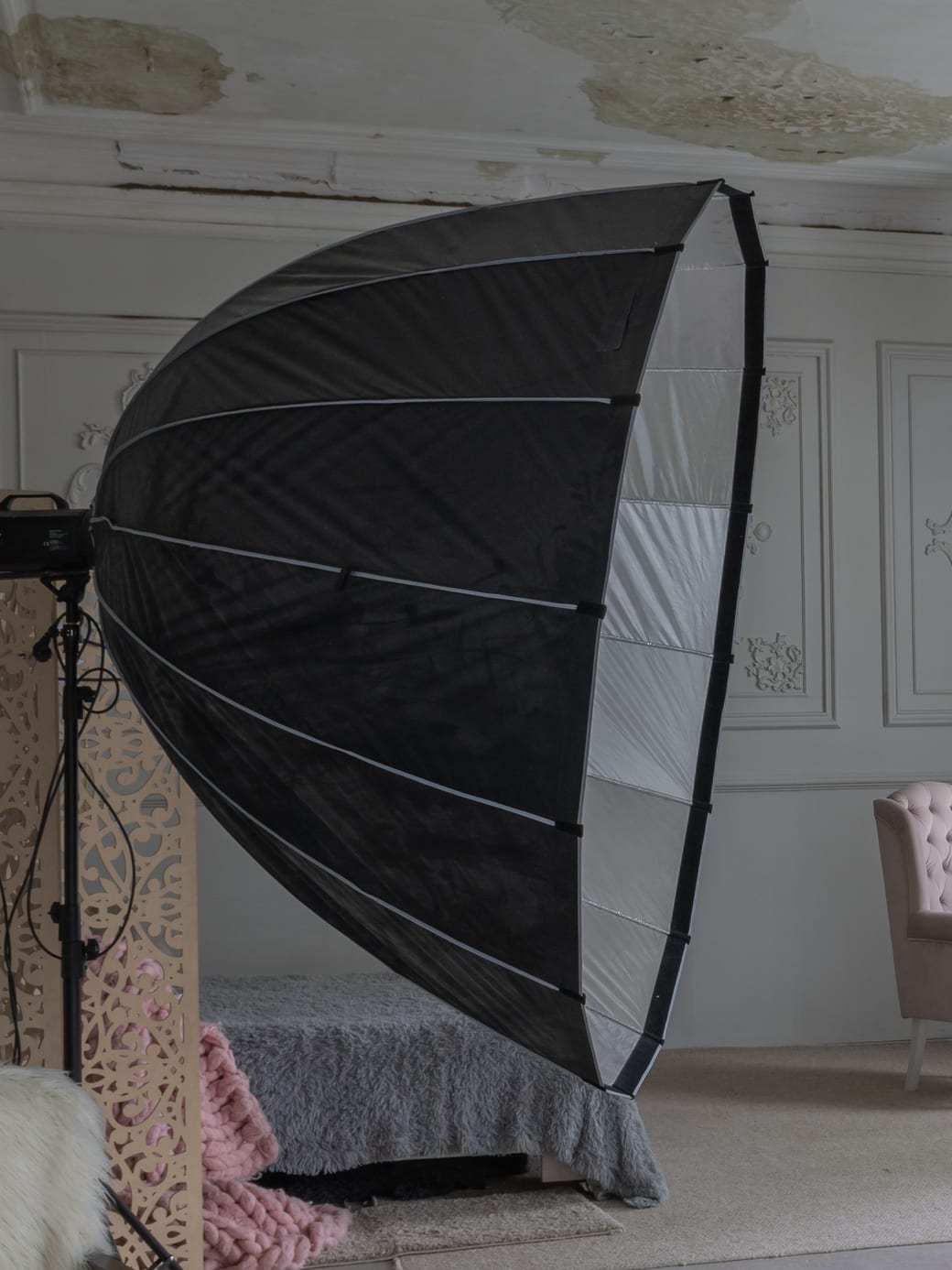 A large deep parabolic softbox on a heavy stand, with the strobe head fitted at its centre, standing in the studio.