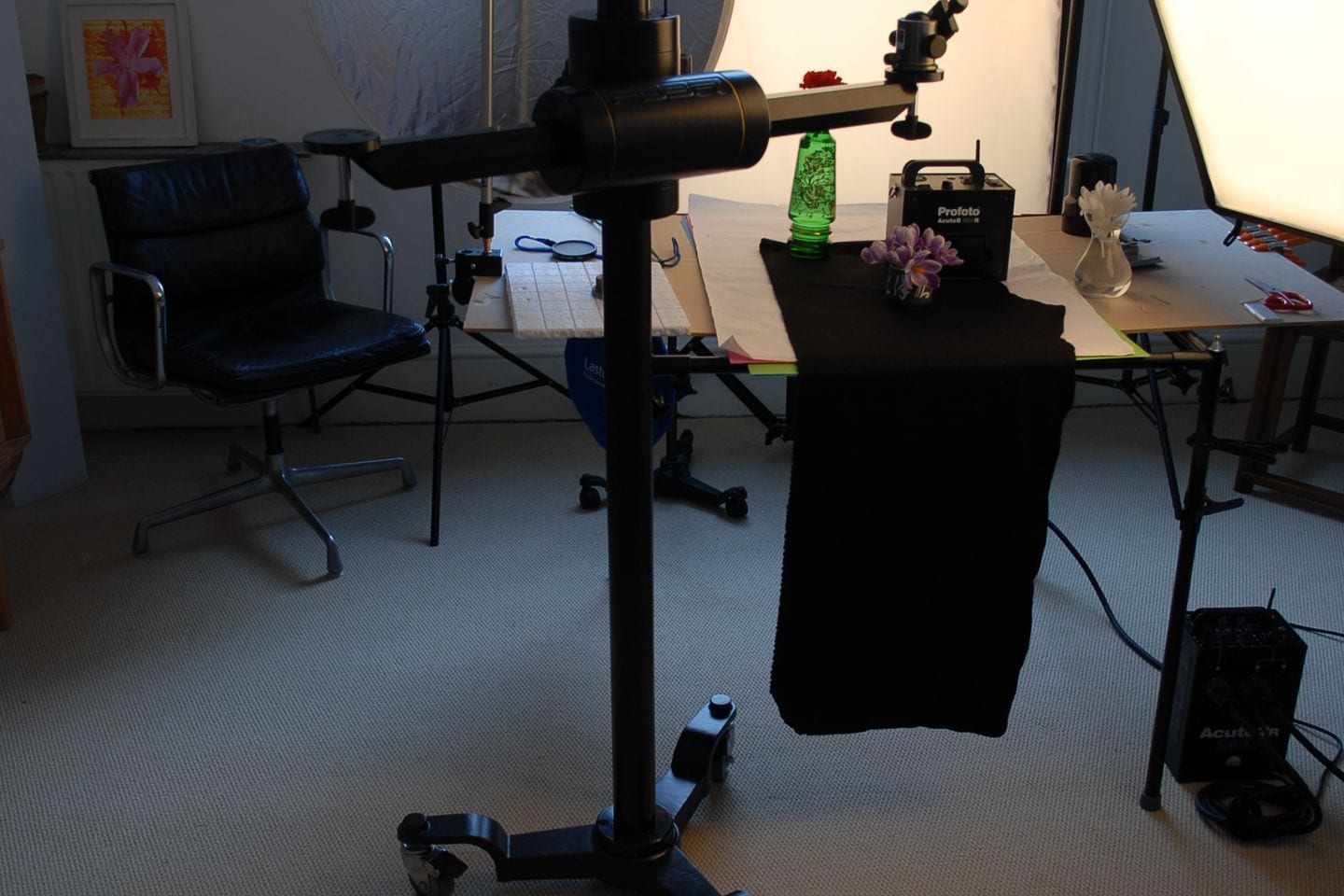 A tabletop set lit by a softbox in a small studio room, with a camera stand in the foreground.