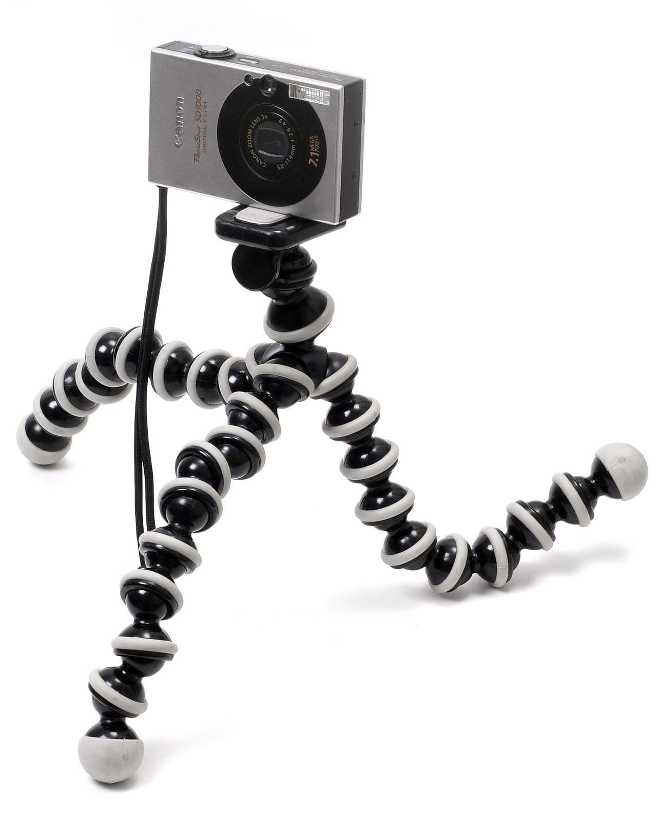 A compact camera clamped to the head of a flexible-legged tripod on a white ground.