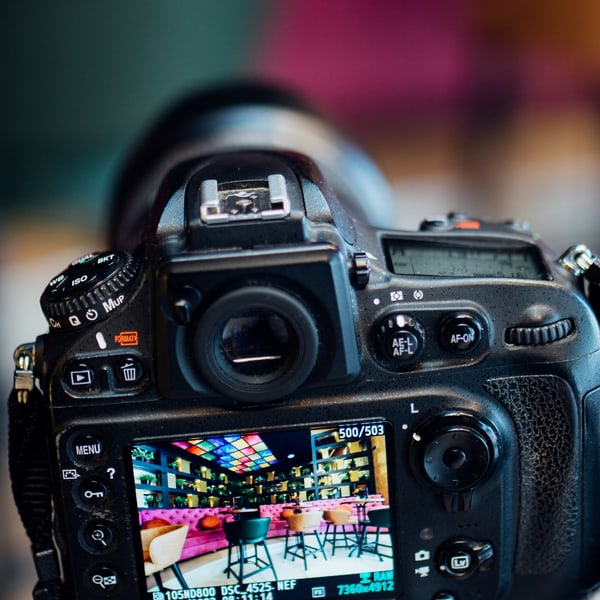 The camera at the shooting position seen from behind, the frame just taken showing on its back screen