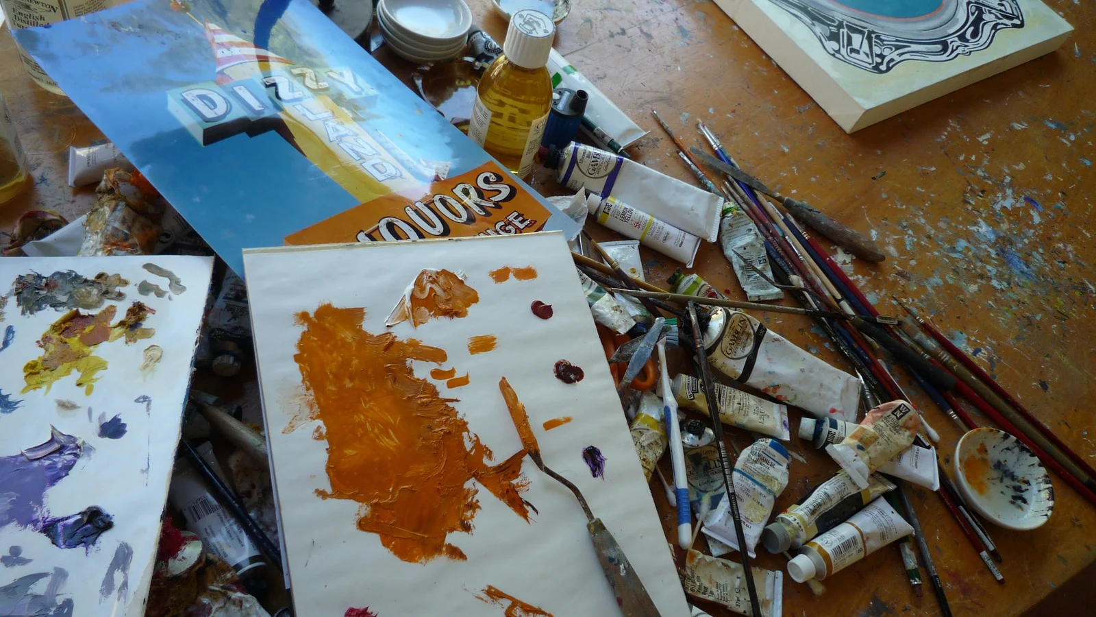 Paint tubes, brushes and a palette knife on a studio desk