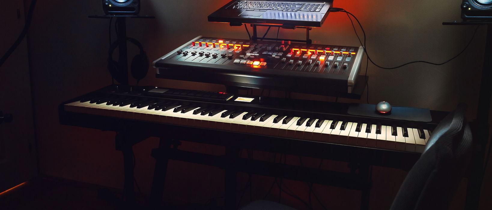 A keyboard and a red-lit controller on a desk in a dark room.