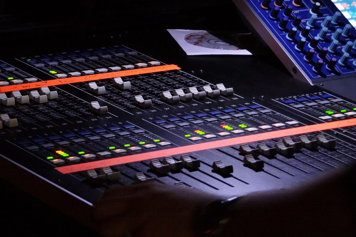 A digital mixing console in a dark room with its channel meters lit.