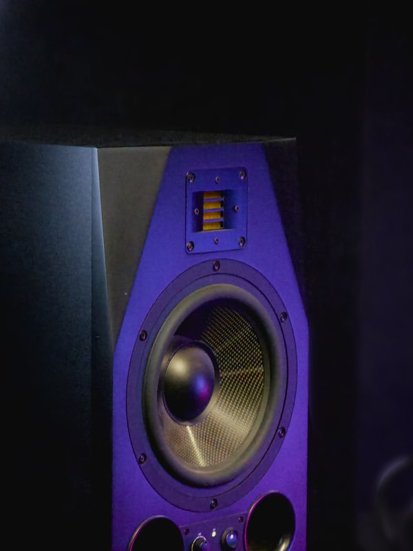 Studio monitor speaker on its stand under a coloured key light