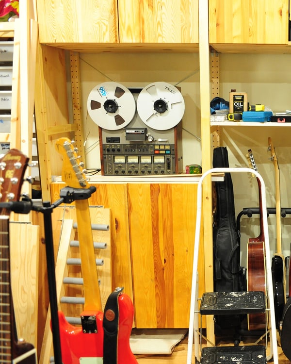 Studio storage wall: a reel-to-reel machine, guitars and instrument cases