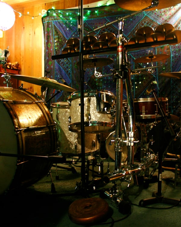 Drum kit and miked concert bass drum in a wood-panelled tracking room