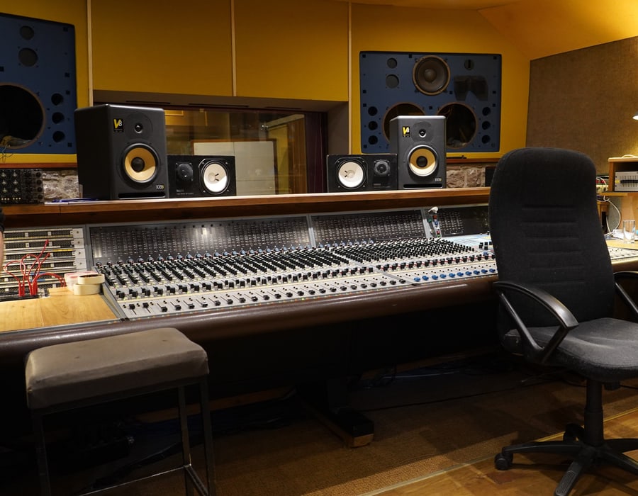 Control room: mixing desk, monitor speakers and a treated rear wall