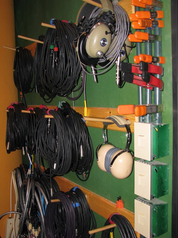 Coiled cable runs on a wall rail with studio headphones hung beside them