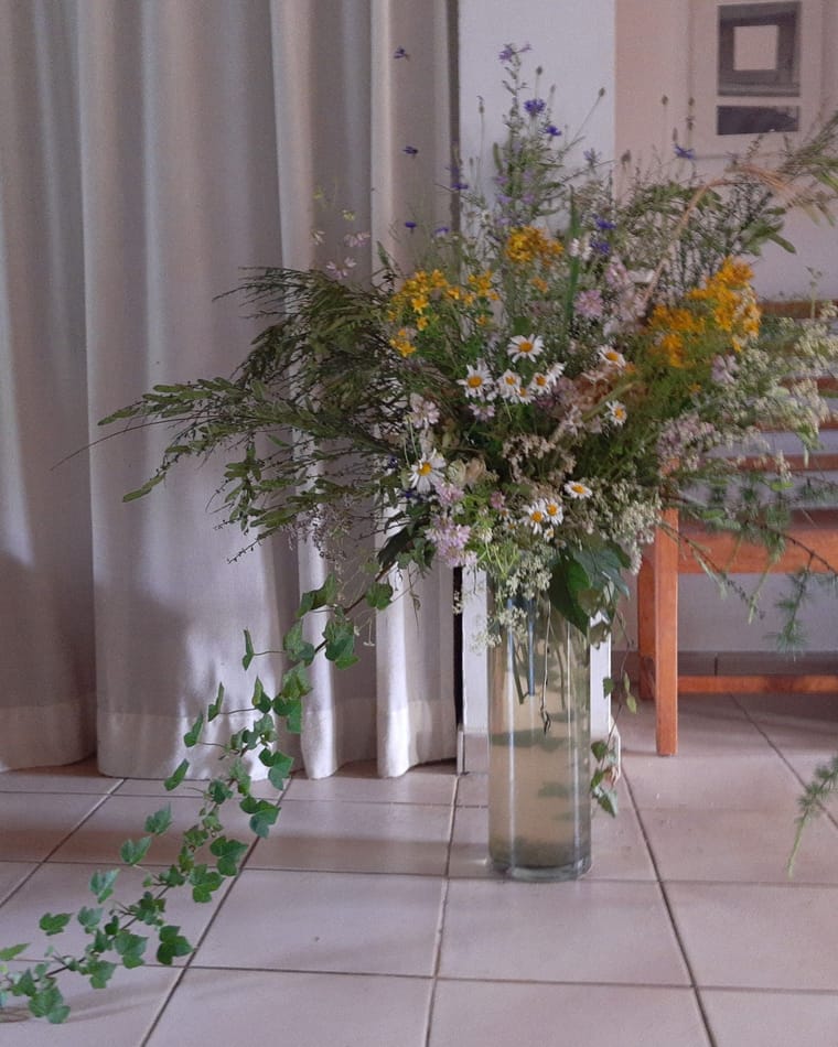 Wildflowers arranged in a tall clear glass vase.