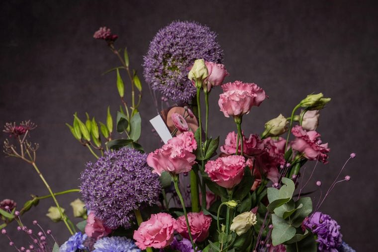 A close view of purple allium heads and pink lisianthus against a dark background.