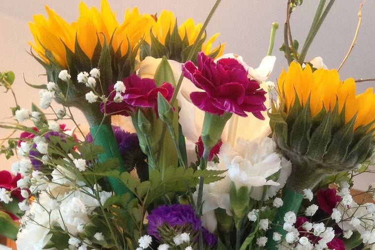 A mixed bunch of sunflowers, magenta carnations and white gypsophila.