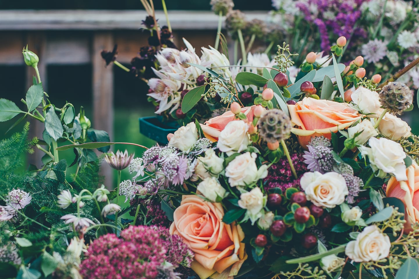 A dense mixed bouquet of peach roses, scabious and astrantia photographed outdoors.