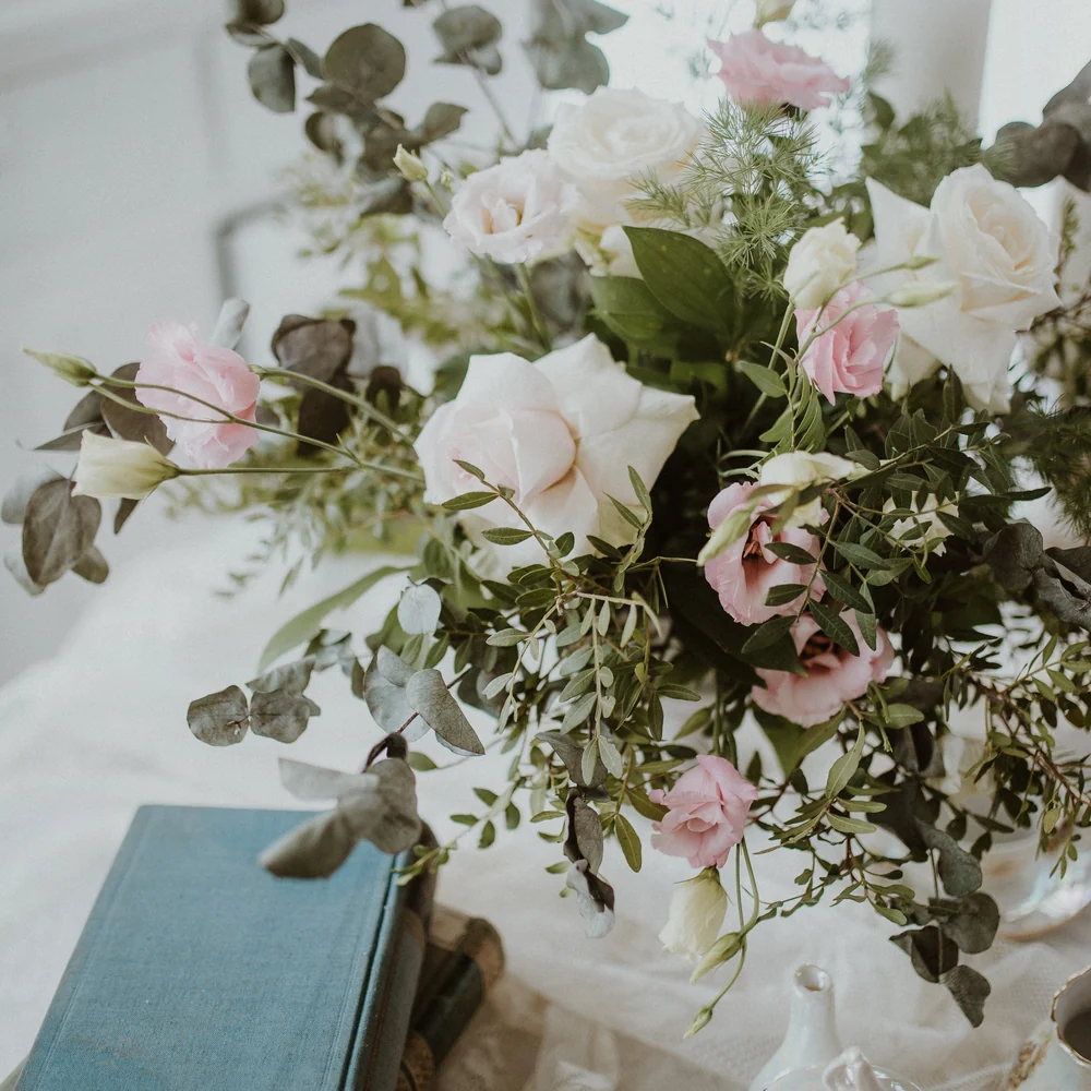 A soft pink and white rose arrangement on a dressed table