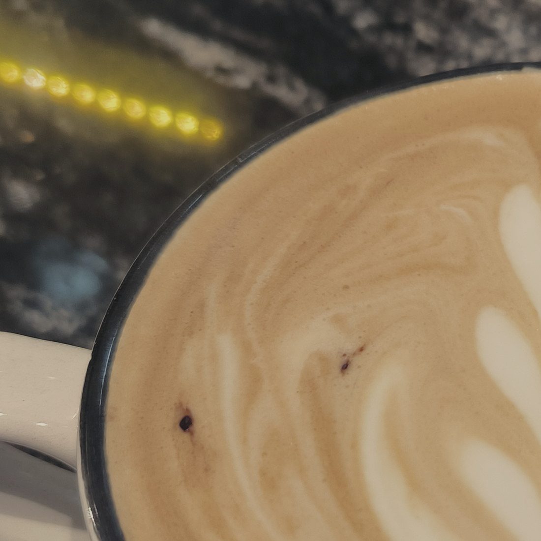 The crema surface of a milk drink photographed from directly above, filling the frame.
