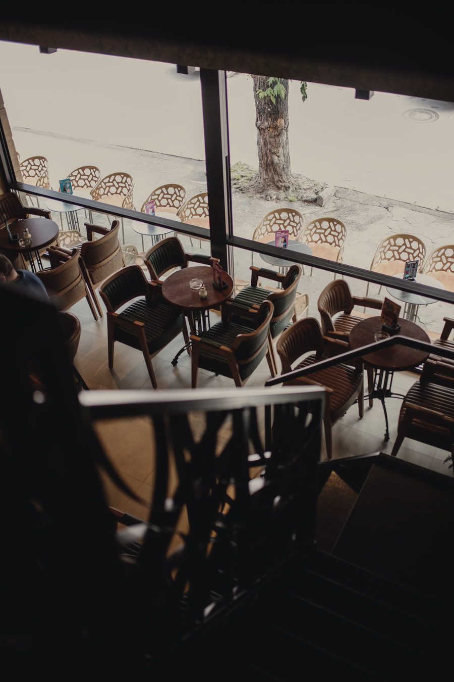 A cafe interior with upholstered seating and tall windows facing a quiet street.