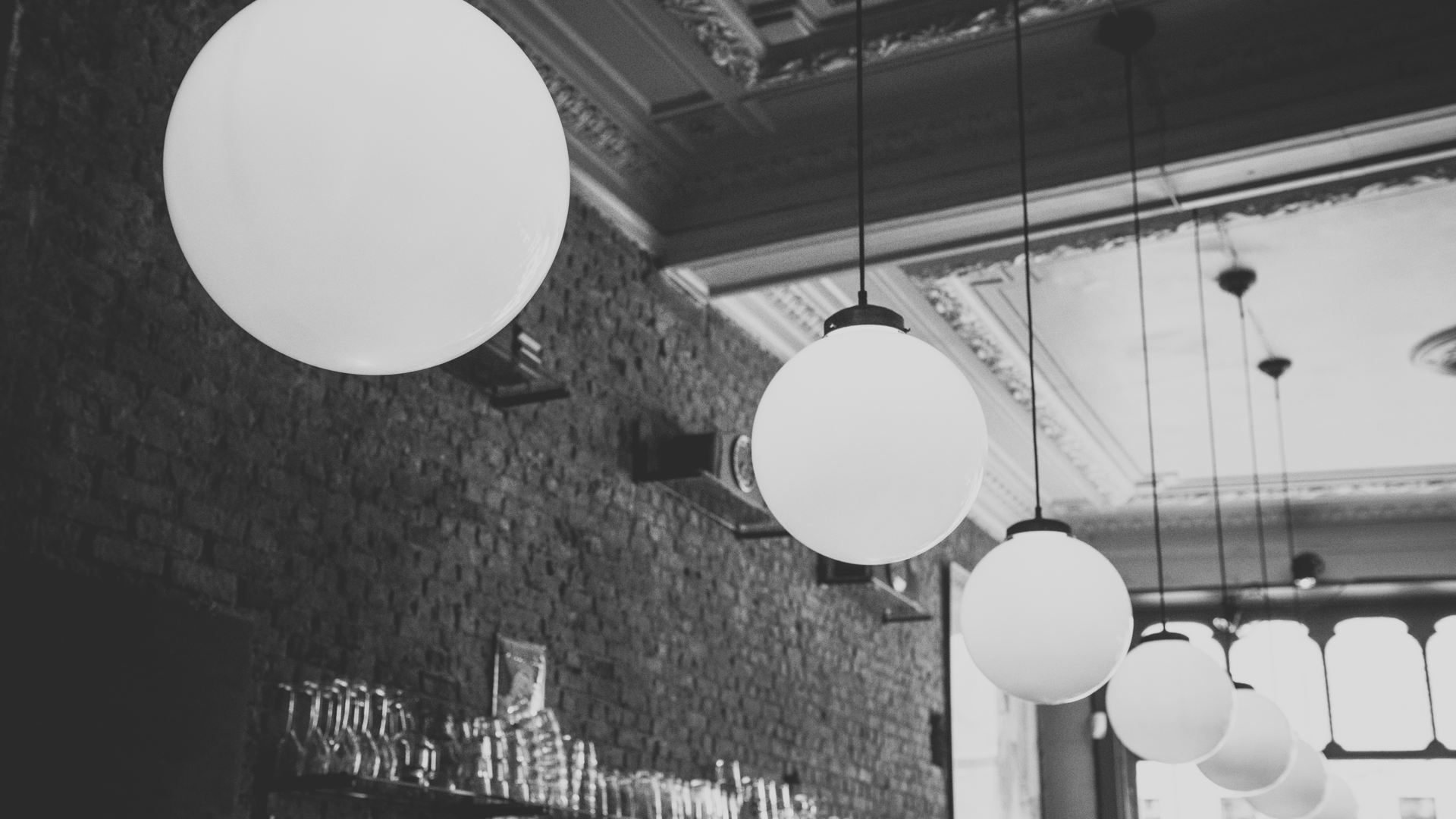 A cafe interior at night with bare filament bulbs hanging on long cords over empty wooden tables.
