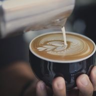 A dark cup of coffee held in two hands.