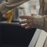 A hand rinsing a glass under a tap.