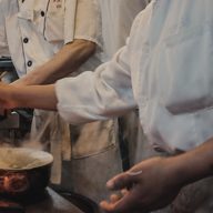 Hands over a pan on an open flame.