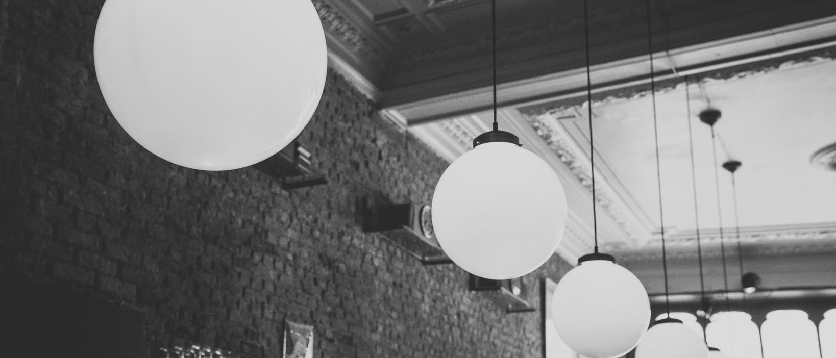 The lantern row over the brick wall at the back of the room, the globes receding towards the long table