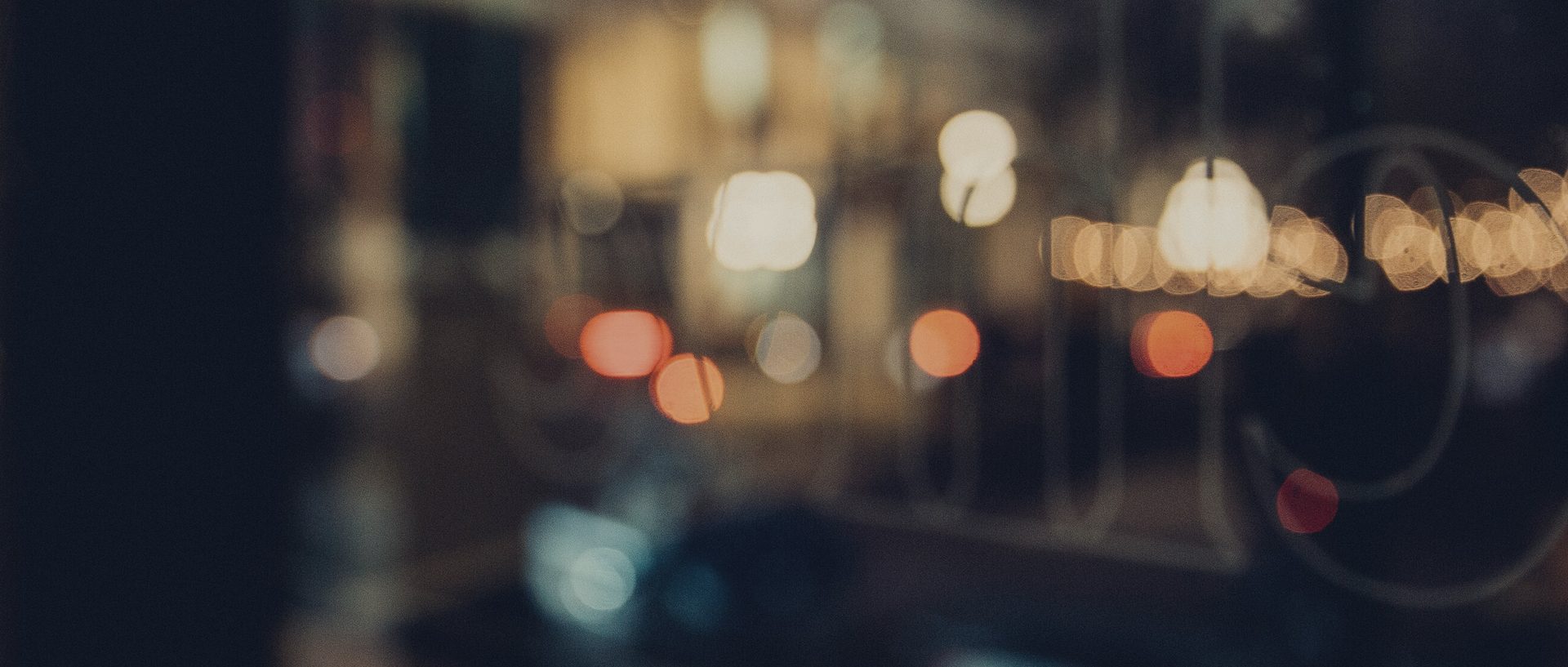 A customer in silhouette at a night window, the street outside reduced to points of light.