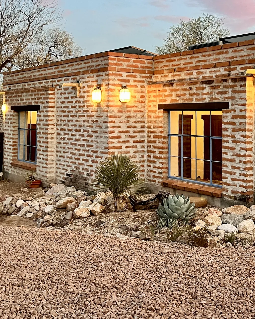 A vertical view of the lit house and its gravel yard.