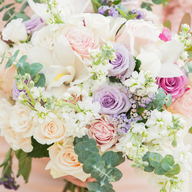 A close-packed bouquet of cream, peach and lilac roses with white stocks.