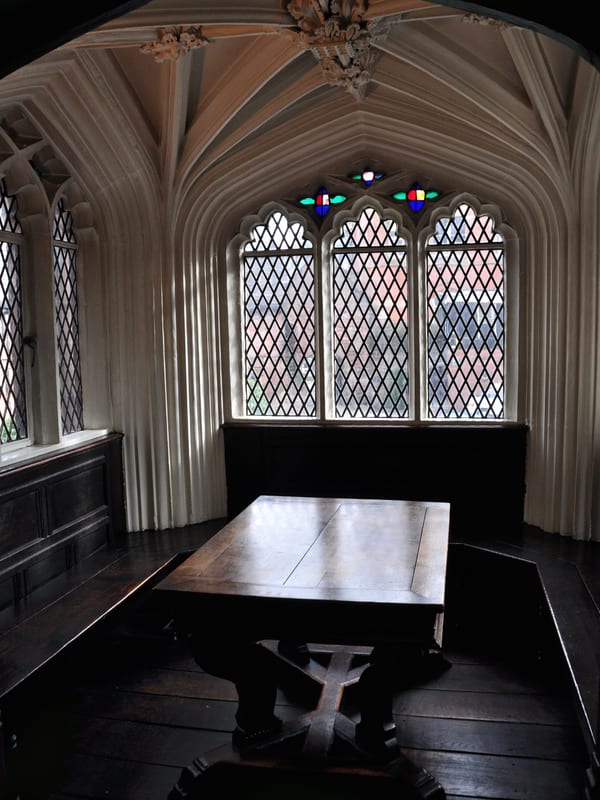 A long study table under a stained-glass window in a reading room