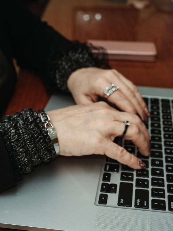 Hands typing on a laptop at a wooden table during an online lesson